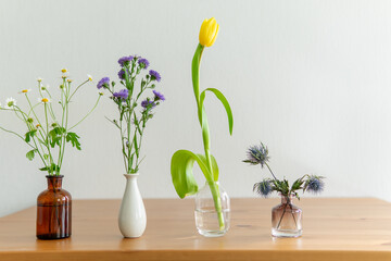 flowers in a vase. different flowers on a wooden table.