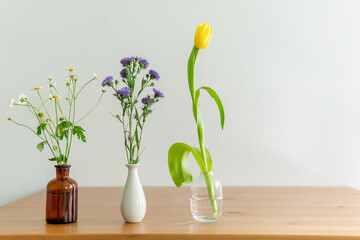 flowers in a vase. different flowers on a wooden table.