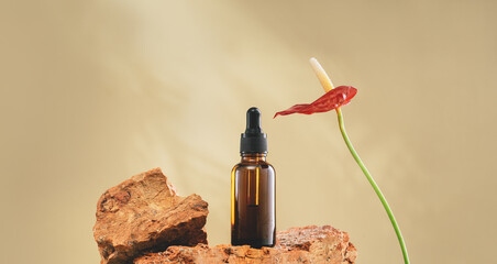 Natural medicine or aroma oil or beauty essence concept vial with dropper on stone podium stand with anturium flower and golden brown background. Face and body spa serum care concept banner