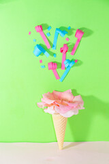 ice cream zone with pink flower above which confetti flies, creative summer party dessert design, green background with copy space