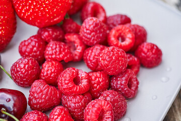 A plate of summer fruit. A close-up of raspberries on a plate.