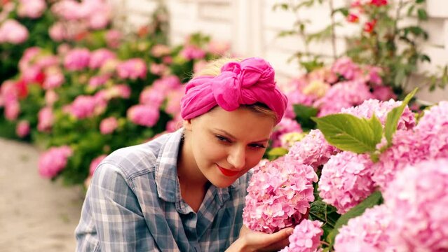 Gardening ib backyard. Beautiful happy young woman enjoying smell in a flowering spring garden Cheerful blond woman planting flowers in garden.