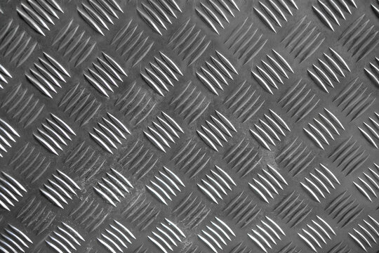 Photo of the texture of a silver embossed metal surface. Aluminum floor in production. A sheet of iron with notches from sliding.