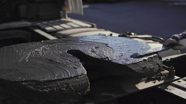 A worker hand smearing trailer fifth wheel coupling with lubricant oil. Semi-truck mechanical maintenance 