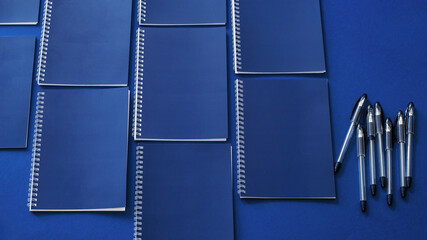 Minimal workspace with blue notebooks on a blue background. Office concept. Mockup. Top view.
