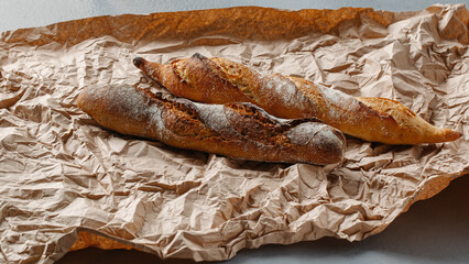 Two long loaves close up on a brown paper background.