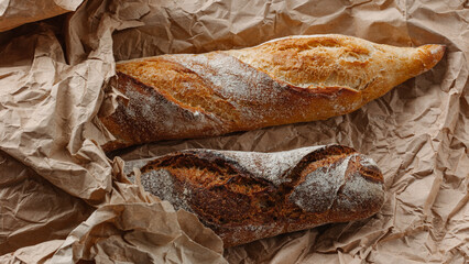 Two long loaves close up on a brown paper background.