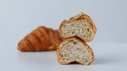Two halves of a croissant on a background of a whole croissant on a white background