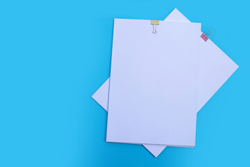 white paper with clip on blue background.