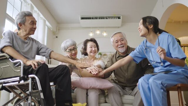 Group of Asian senior people with some diseases in nursing home forming hands stack to build morale for yourself