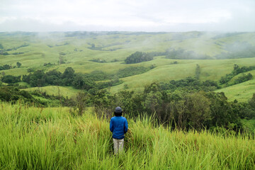 Naklejka na ściany i meble Man standing in middle of green hills. West Kalimantan.