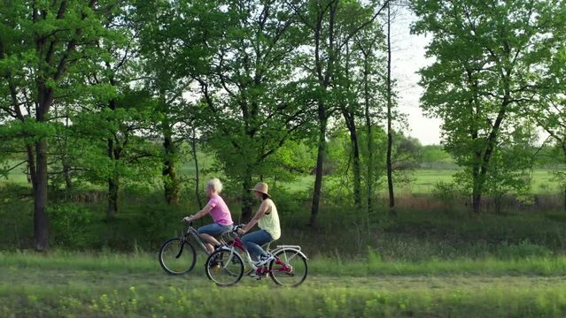 Active recreation in nature cycling. Two girls on a bike ride in the park, lifestyle video.