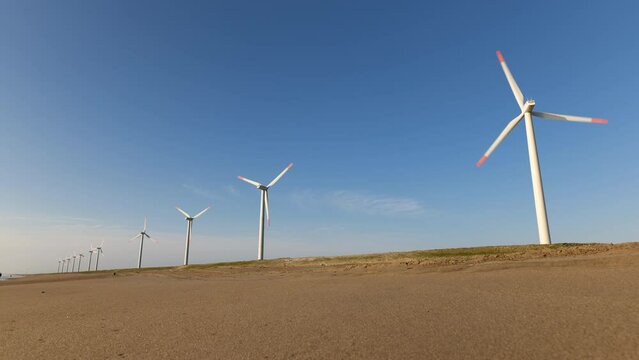 青空と海岸の風力発電の風車。茨城県神栖市須田浜海岸の波崎ウインドファーム。