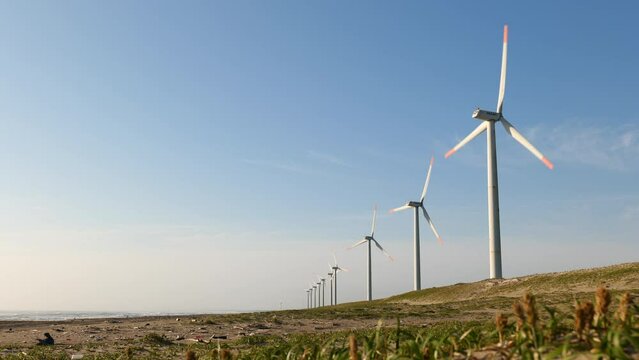 青空と海岸の風力発電の風車。茨城県神栖市須田浜海岸の波崎ウインドファーム。