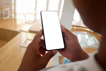 Mockup picture of business man’s hands holding smart phone with white blank screen in modern place.