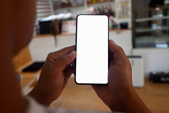 Mockup picture of business man’s hands holding smart phone with white blank screen in modern place.