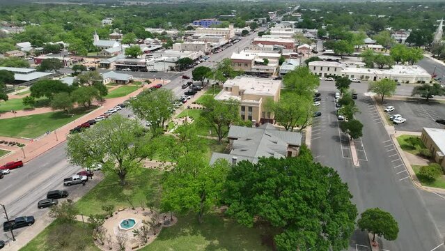 Aerial Fredericksburg Texas main street part 1. Settled 1846 by German immigrants to south Texas. Historic homes and businesses. Tourism for crafts, dinning and family exploration in hill country.