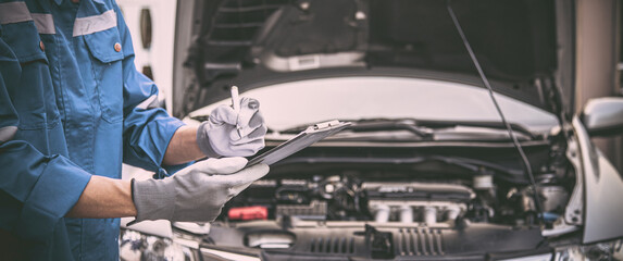 Car care maintenance and servicing, Close-up hand technician auto mechanic checking inspection list after repairing change spare part car engine problem and car insurance service. - obrazy, fototapety, plakaty