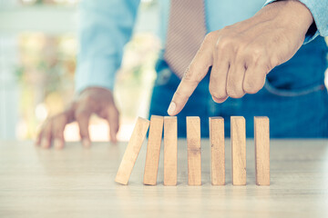 Close-up hand prevent wooden block not falling domino concepts of financial risk management and...