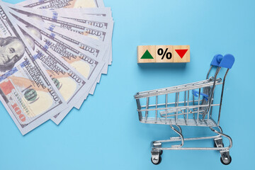 A picture of trolley, fake money and percentage, up ,down arrow. Inflation and buying power concept