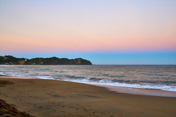 Fototapeta na wymiar beach at sunrise with beautiful sky with orange and blue colors and waves in sayulita nayarit
