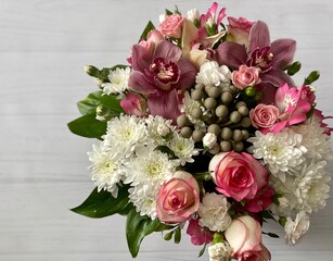 A beautiful bouquet of different flowers in a round box on a wooden light textured background. Concept of greeting or invitation card. Thank you card, copy space.