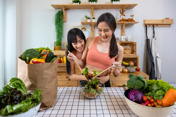 Asian couple of same sex marriage cooking healthy salad together in kitchen during pride month to...