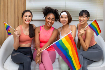 Group of diversity woman in sport wear holding LGBTQ rainbow flag for pride month to promote...