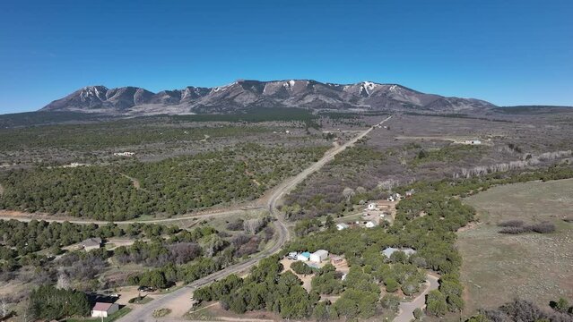Aerial Monticello Utah rural neighborhood pull part 1. Settled in July 1887 by pioneers from The Church of Jesus Christ of Latter-day Saints. Farming, ranching, and uranium mining. Mountain valley.