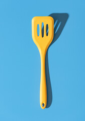 Silicone spatula minimalist on a blue table. Yellow stapula top view.