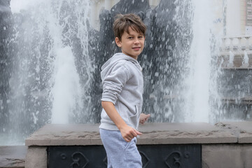 White caucasian boy at the fountain is delighted but beware of water splashes