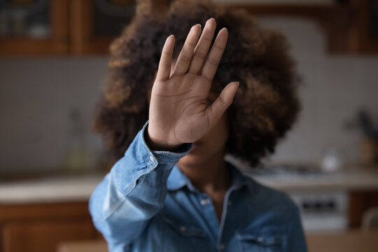 Unknown Afro American Female Stretch Hand To Camera Show Stop No Gesture To Racial Gender Discrimination Harassment Abortion War Genocide. Focus On Open Palm In Front Of Blurred Face Of Young Woman