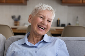 Fototapeta na wymiar Happy and healthy. Headshot portrait emotional positive old lady with stylish short hairdo laugh on joke demonstrate toothy smile. Attractive elderly female pensioner look at camera feel joy good mood
