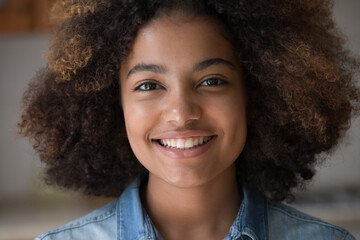 Closeup face attractive optimistic African teen lady look at camera with perfect white smile...