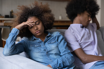 Disappointed tired Black teen girl ignoring offended boyfriend, thinking over conflict, arguing,...