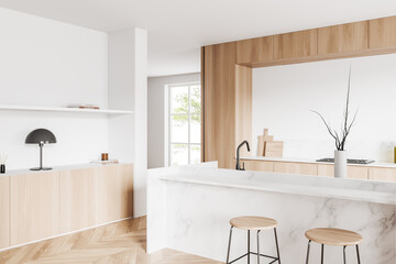 Light kitchen interior with island and seats, shelves and kitchenware, window