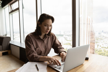 Focused remote employee working at laptop from home, using online virtual app or service....