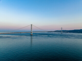Aerial view of sunset glow on horizon behind Akashi Kaikyo, the world's longest suspension bridge