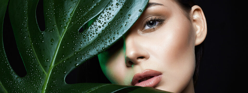 beautiful girl in palm leaves. Beautiful young woman with Make-up