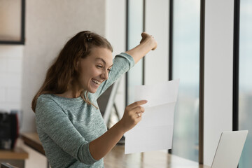 Happy excited student girl reading paper letter with good news, receiving admission letter from university, college, school, smiling, laughing, shouting for joy, celebrating achieve, success - obrazy, fototapety, plakaty