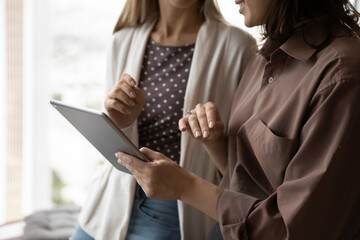 Female business coworkers using tablet together, watching virtual online presentation, discussing...