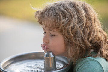 Kid drinking water from outdoor water fountain outdoor. Thirsty child.