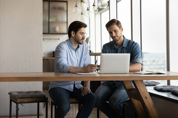 Corporate mentor explaining content on laptop to intern, training new employee, telling about work...
