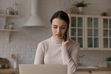 Serious young customer woman making call to client support service, talking on mobile phone at...