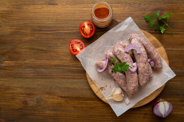 Uncooked barbecue sausages and spice on wooden surface