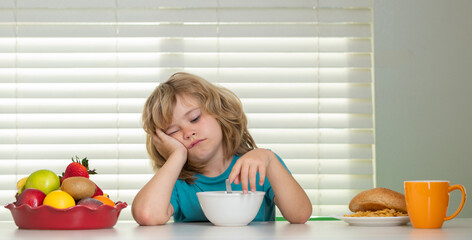 Portrait of kid with no appetite. Concept of loss of appetite. Schoolchild eating breakfast before...