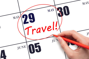 Hand drawing a red circle and writing the text TRAVEL on the calendar date 29 May. Travel planning.