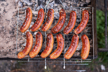 Tasty Sausages grilling on charcoal grill grate