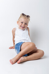 Blond child with sunglasses posing on a light background in the studio