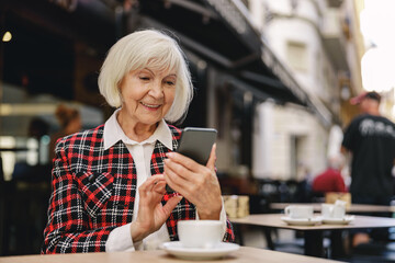 Trendy pensioner female enjoying coffee break outdoors